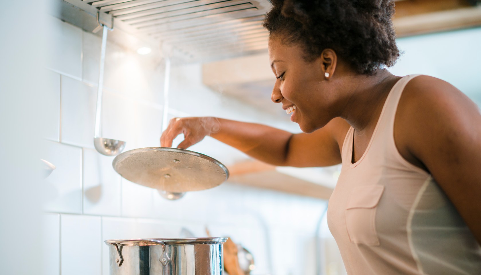 Young pretty black woman make soup in kitchen