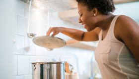 Young pretty black woman make soup in kitchen