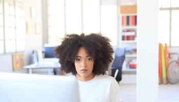 Young african woman sitting at workplace