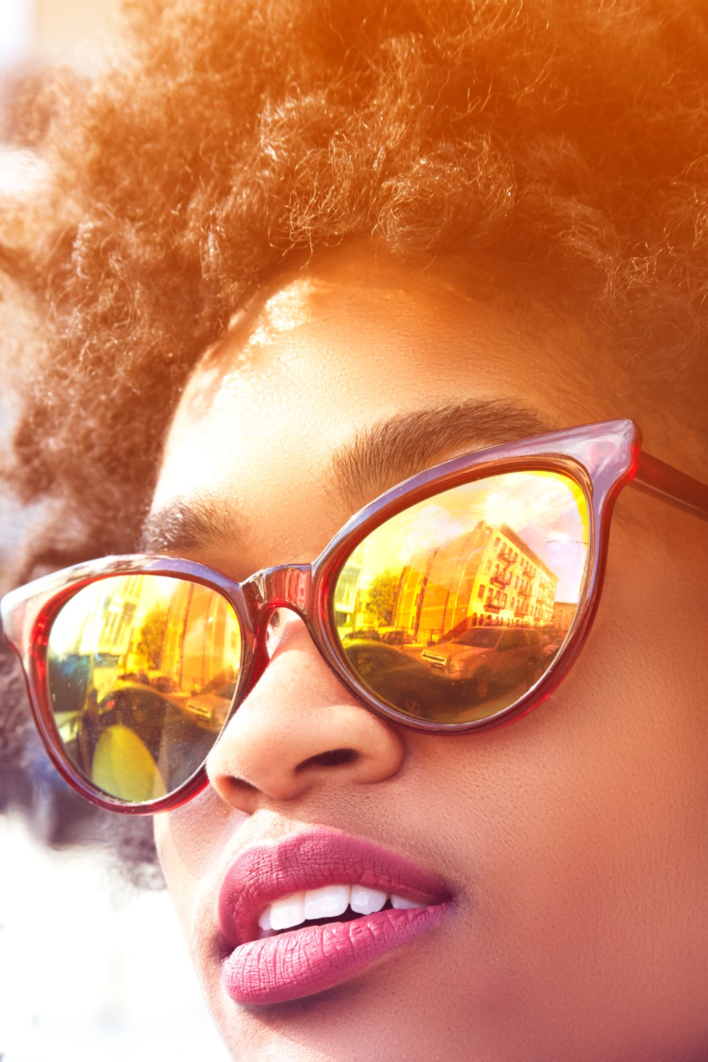 Close up portrait of young female fashion blogger with afro hair and mirrored sunglasses, New York, USA