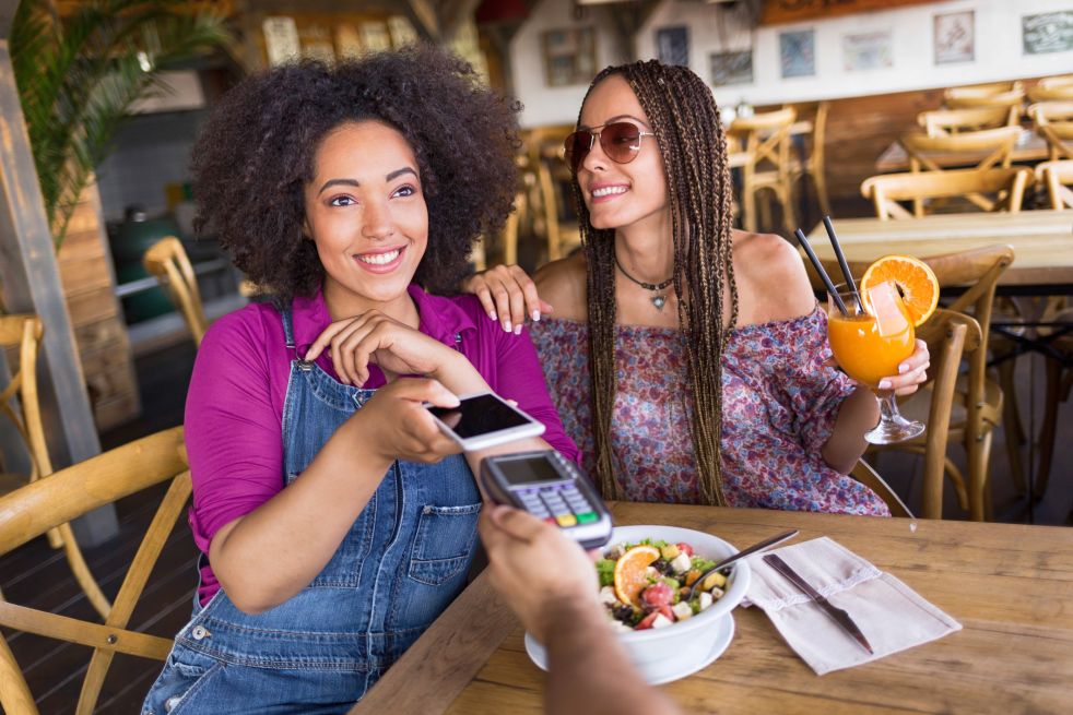 Cheerful frineds using smart phone for mobile payment