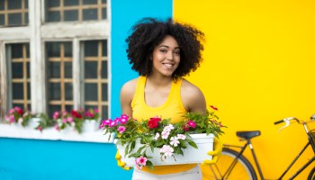 Smiling woman with bike carrying flowers in pot