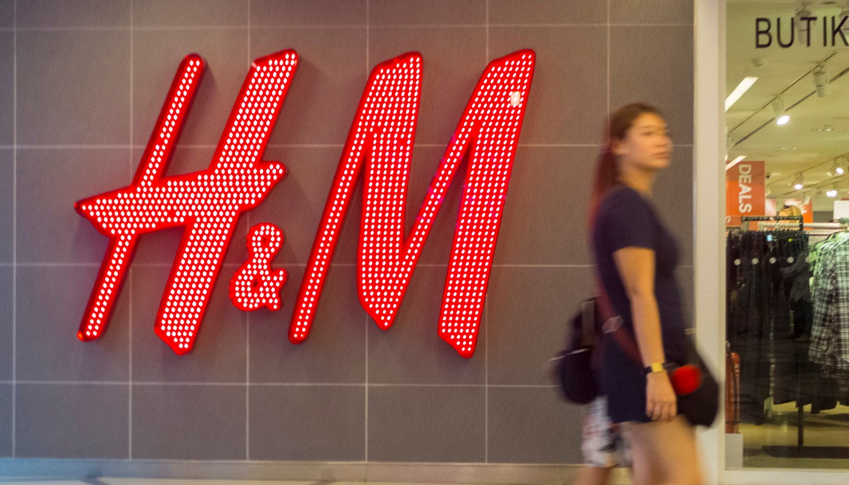 A woman seen walking in front of the H&M shop. Malaysia...