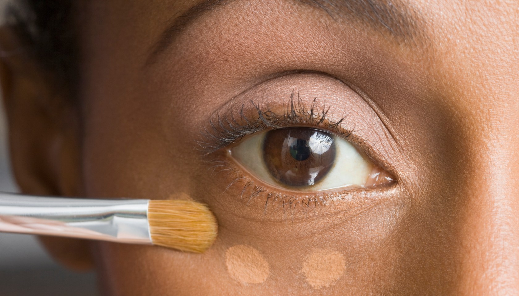 African American woman applying makeup