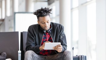Young african using digital tablet in airport lounge