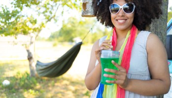 Smiling woman drinking green cocktail