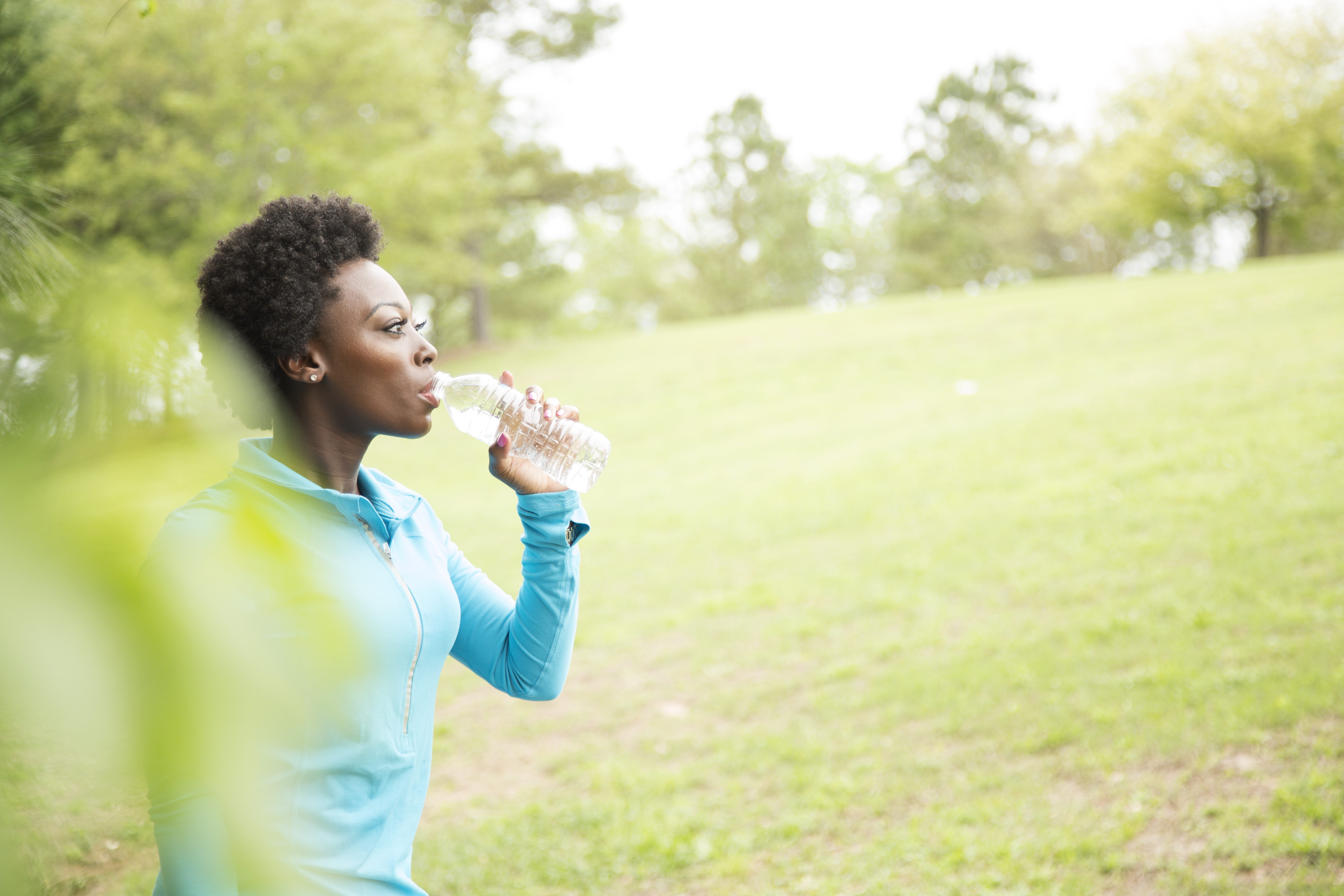 One African descent woman takes water break in neighborhood park.