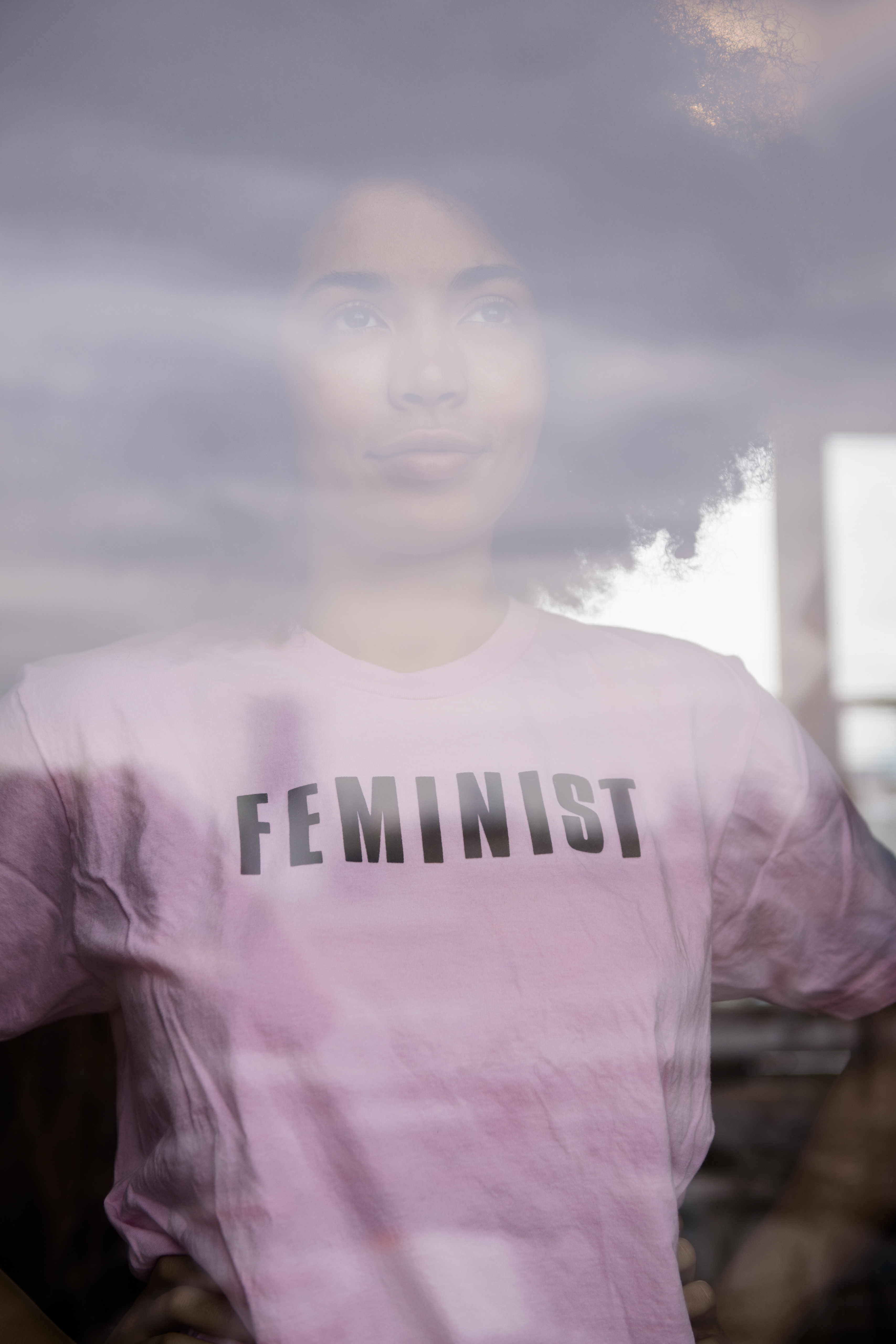 African American woman wearing feminist t-shirt behind window