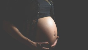 Midsection Of Pregnant Woman Against Black Background