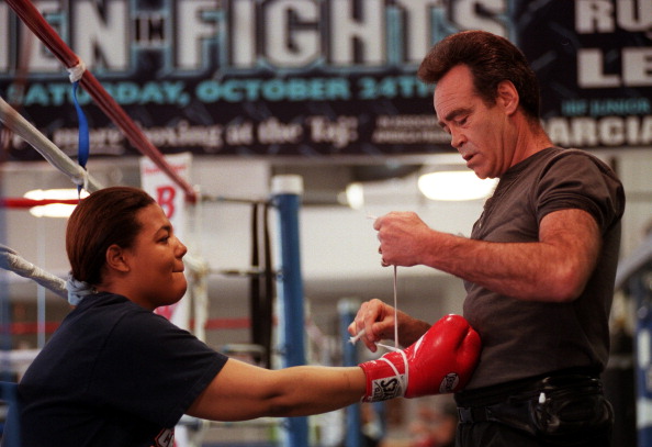 Boxer Freeda Foreman, daughter of former heaveyweight champion George Foreman, puts her gloves on with trainer Larry Goossen before working out at America Presents Gym in Denver.