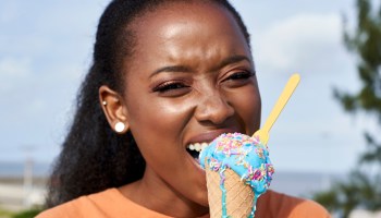 Portrait of young woman eating lightblue icecream outdoors