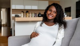Thoughtful pregnant African American woman relaxing at home