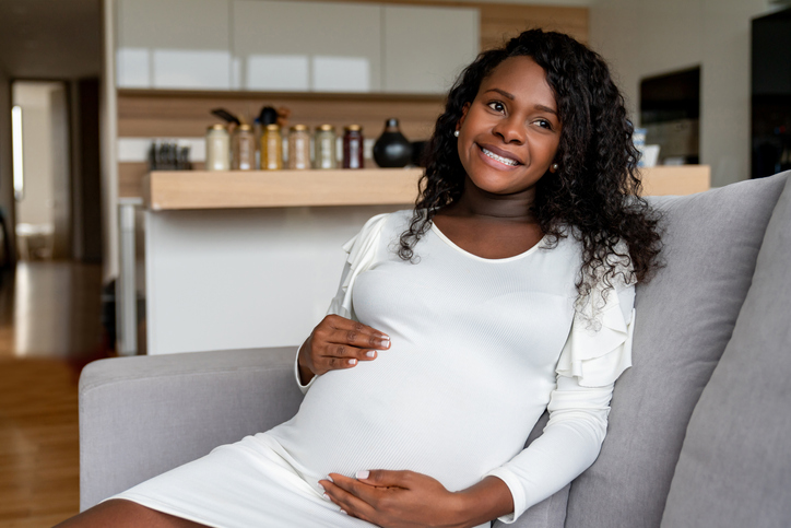 Thoughtful pregnant African American woman relaxing at home