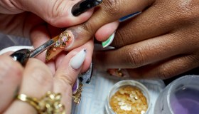 A close-up of a nail artist creating a chandelier nail manicure