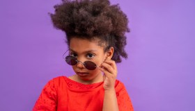 Ethnic kid girl looking camera lowering sunglasses