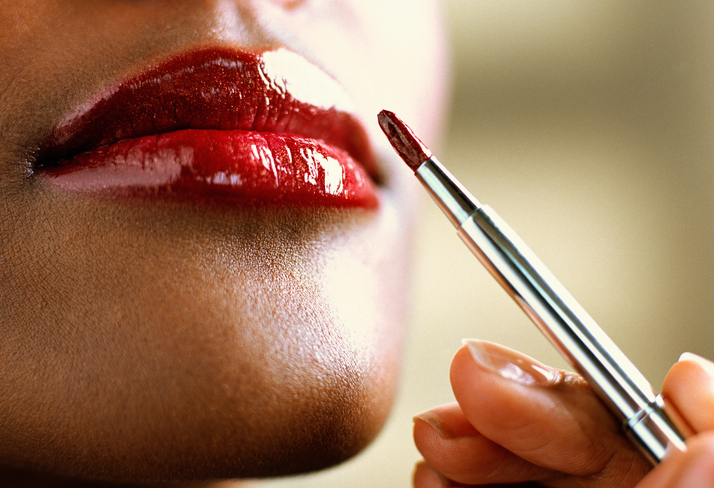 Woman applying lipstick with brush, close-up