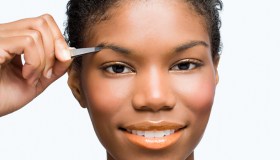 Young woman plucking eyebrows