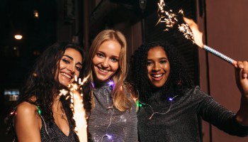 Portrait Of Cheerful Female Friends With Sparklers In City At Night