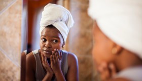 Young woman checking her skin in the mirror. Cape Town, Western Cape Province, South Africa