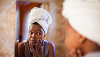 Young woman checking her skin in the mirror. Cape Town, Western Cape Province, South Africa