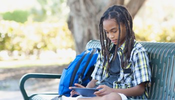 Boy (13-15) sitting on bench with tablet