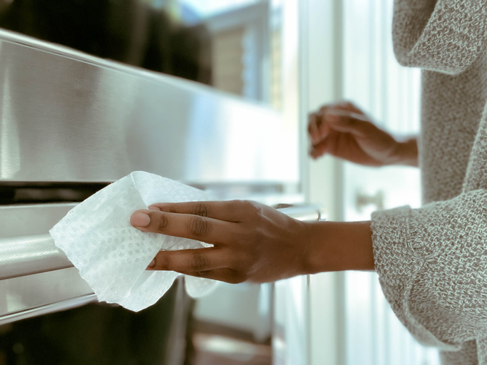 Woman Cleans Oven Handle Using Disinfectant Wipe