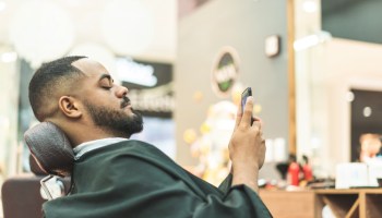 African man using cell phone in barbershop