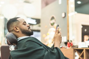 African man using cell phone in barbershop