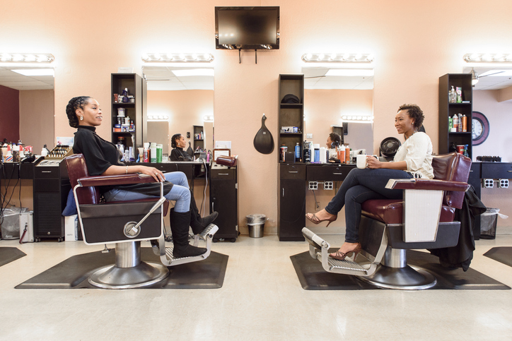 Two women sat drinking coffee in a hair salon