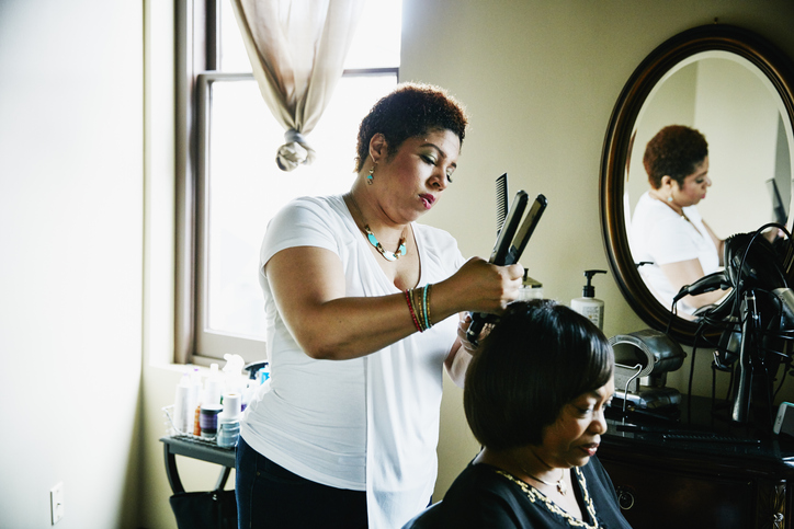 Salon owner straightening hair of client in salon