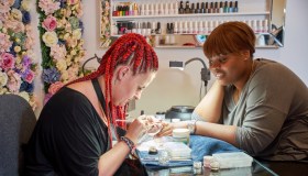 A nail artist and her client having her nails manicured.