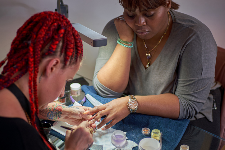 A close-up of a nail artist creating a chandelier nail manicure