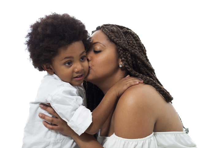 Black loving mother kissing her son on cheek