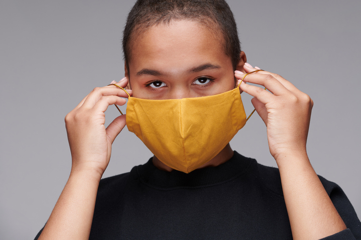 Portrait of young Black woman wearing yellow mask to protect herself against coronavirus