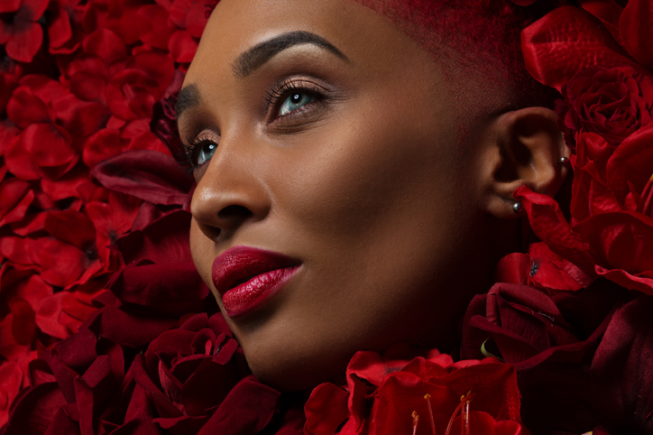 Beautiful mixed race woman in a bed of red flowers