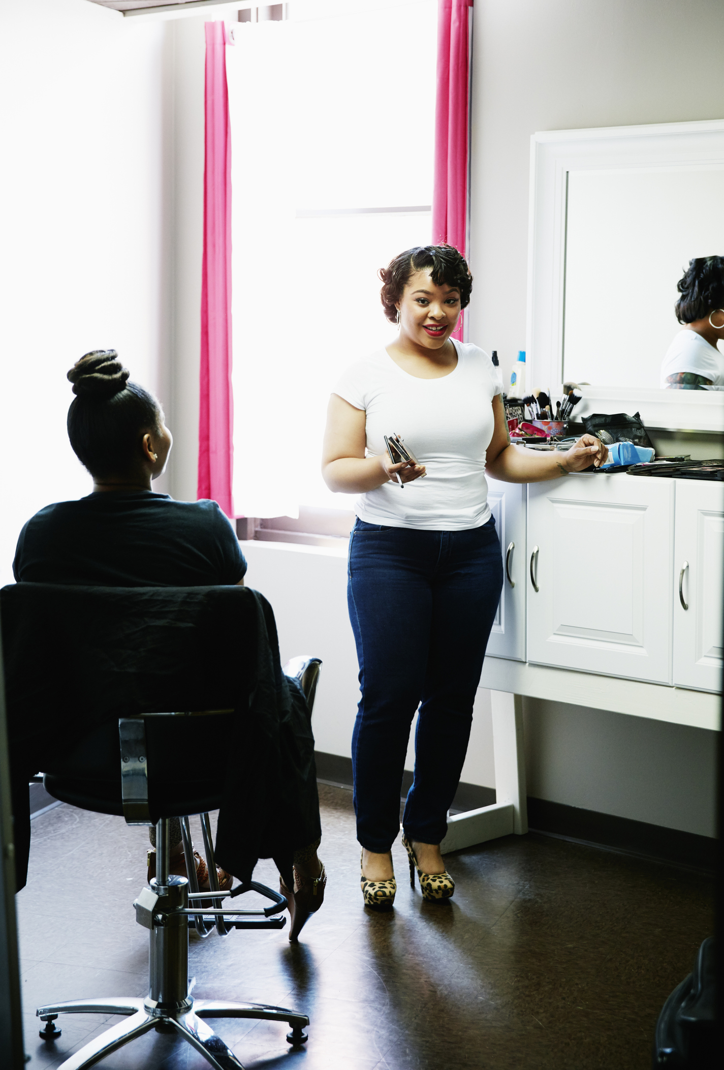 Smiling makeup artist in salon with client