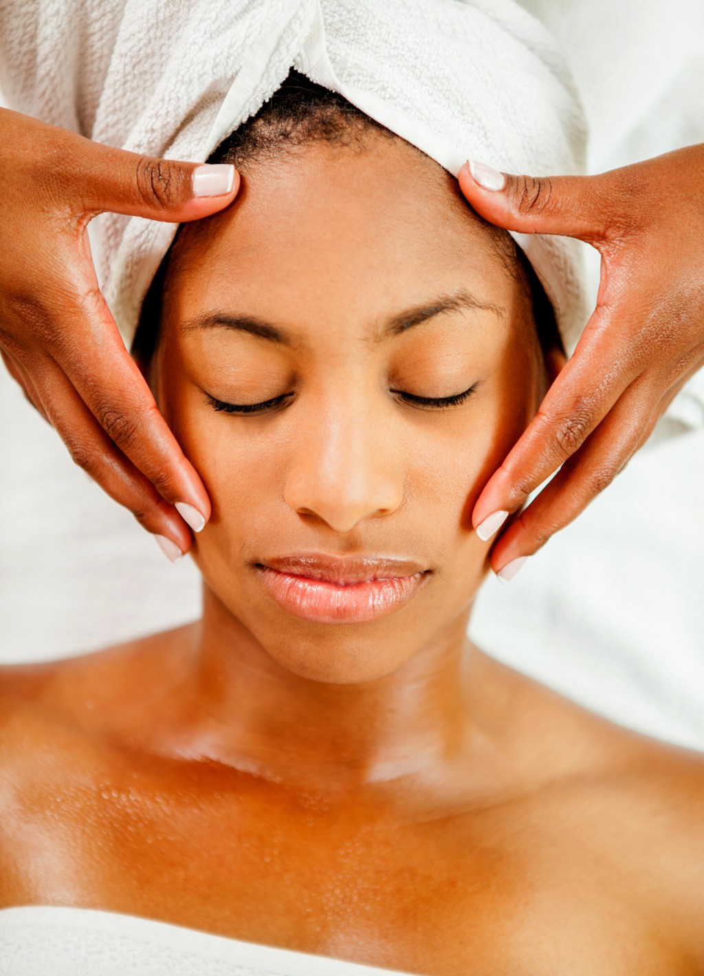Beautiful black young woman getting a face massage looking very relaxed
