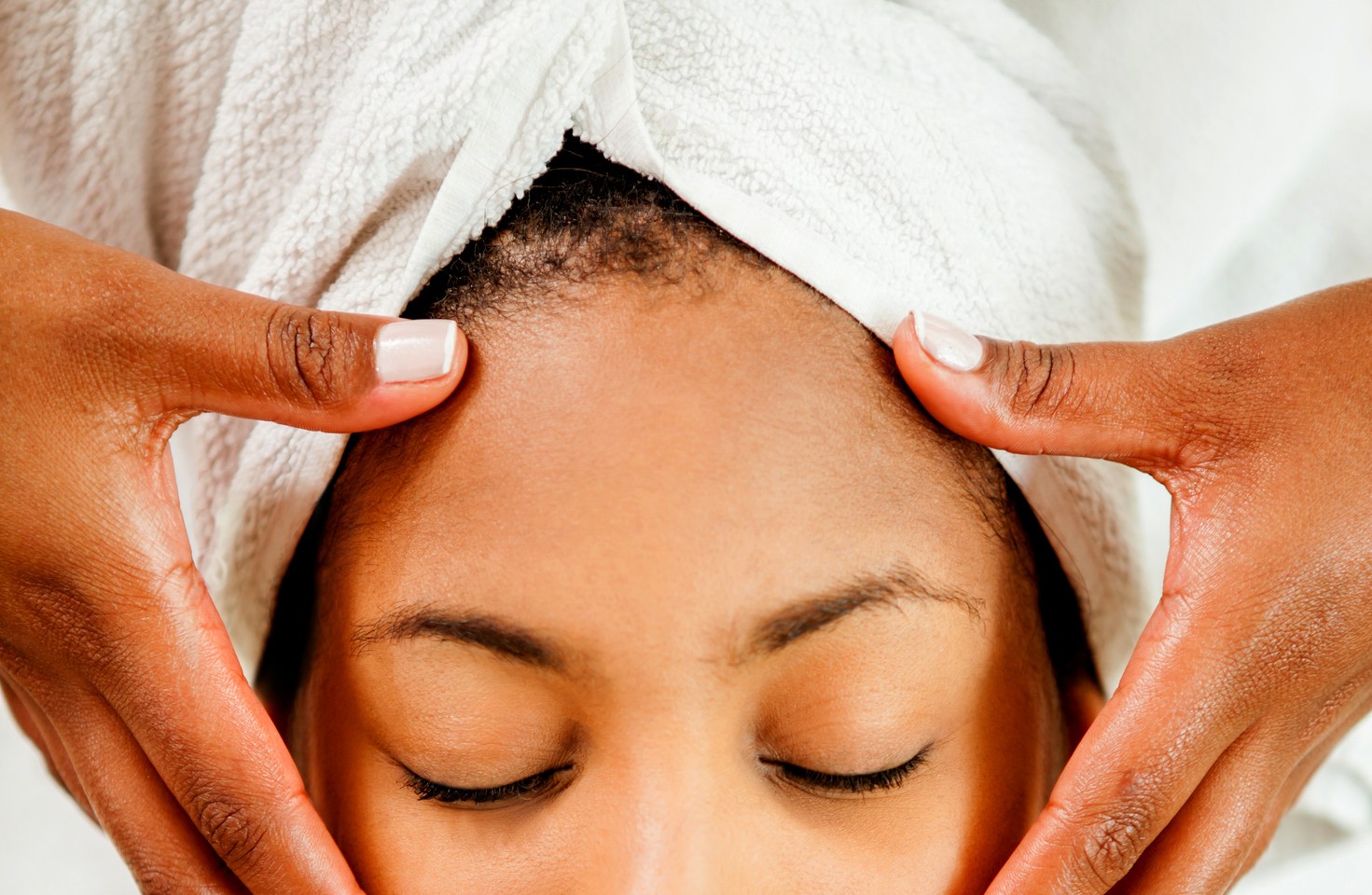 Beautiful black young woman getting a face massage looking very relaxed