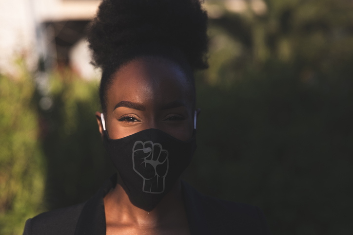 Woman wearing a black face mask with a fist printed on it