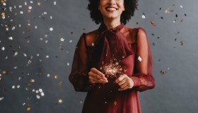 Portrait of an Anonymous Smiling Woman in a Festive Red Dress Holding Sparklers, Celebration Concept