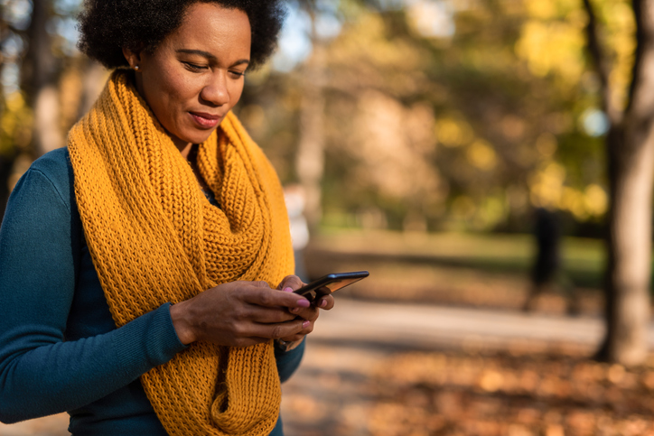 African American woman using mobile phone at public park.
