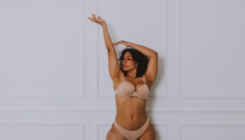 Young Woman Wearing Lingerie Standing Against Wall