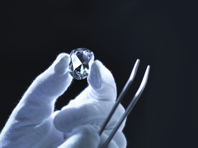 Jeweller inspecting replica diamonds with gloved hand