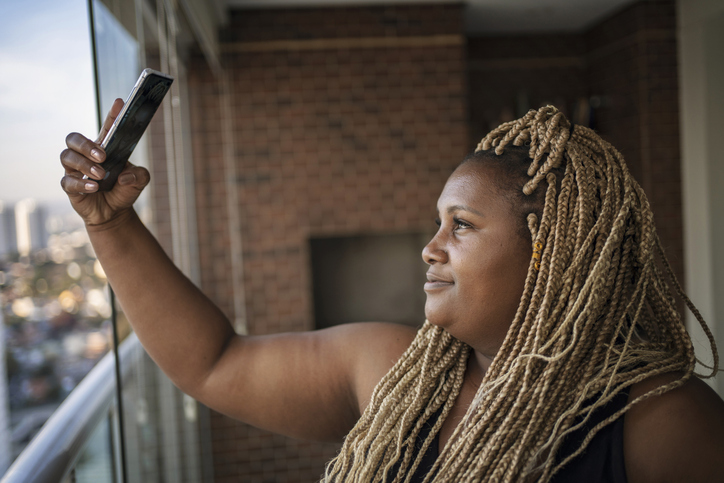 Portrait of a beautiful African American woman with braided hair doing selfie.