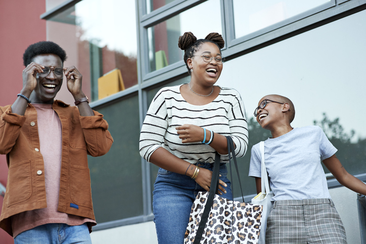 Cheerful young friends against window at college