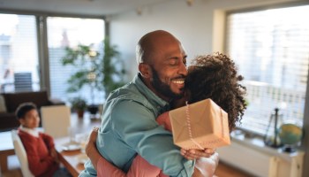 Cheerful African American father getting present by her daughter, celebrating.