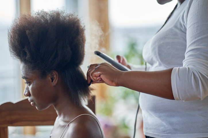 A young woman having her hair straightened. In preparation for hair braids