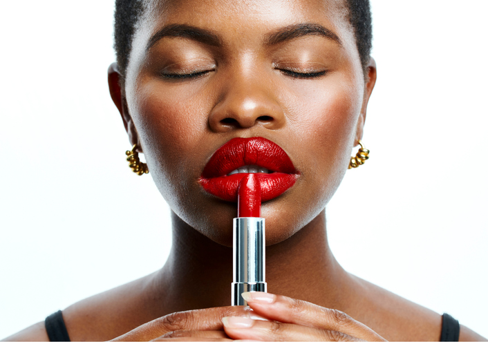 Beauty, makeup and confident black woman applying red lipstick against a white background. Closeup of a beautiful African American female face enjoying self care during grooming and skincare routine