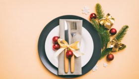 Christmas table place setting with christmas decor and plates, kine, fork and spoon. Christmas holiday background. Top view