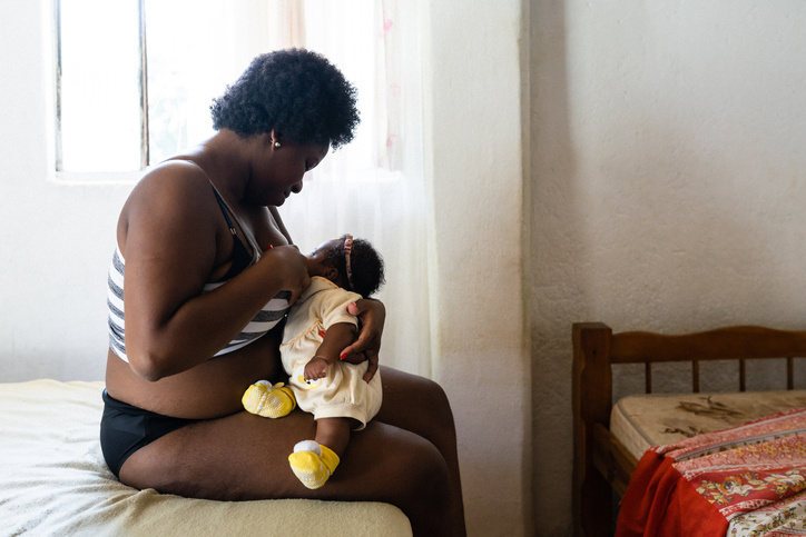 black Mother breastfeeding daughter in bed
